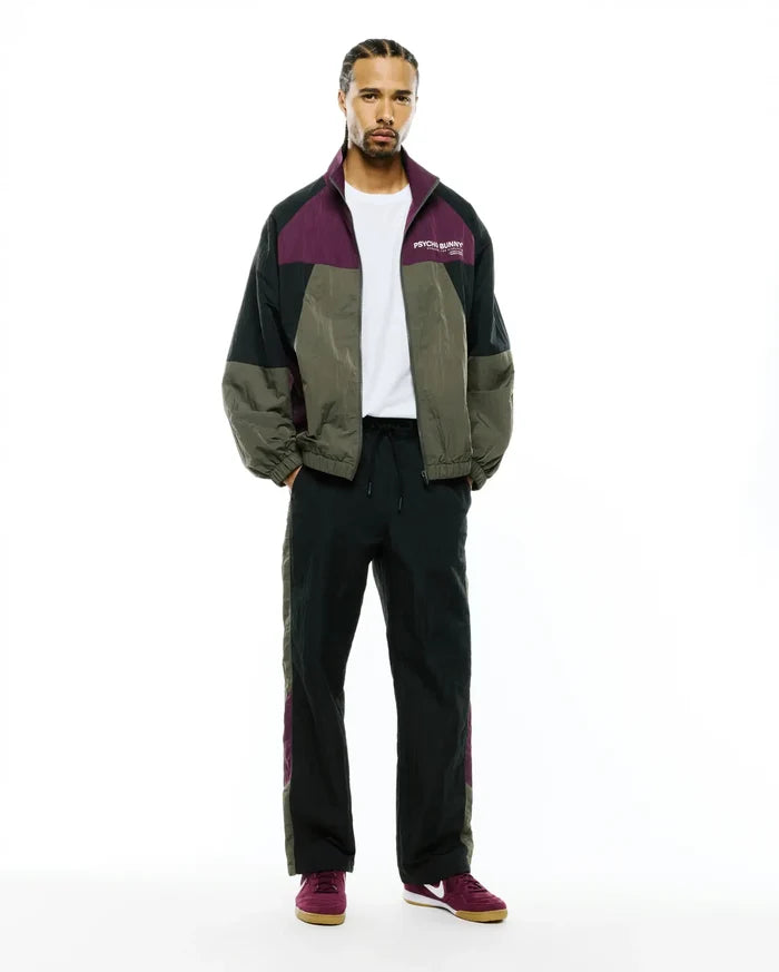Mens Alder Nylon Colorblock Jacket, a relaxed fit crinkled nylon jacket in dark green, black, and plum, featuring a white Psycho Bunny text logo on the left chest.