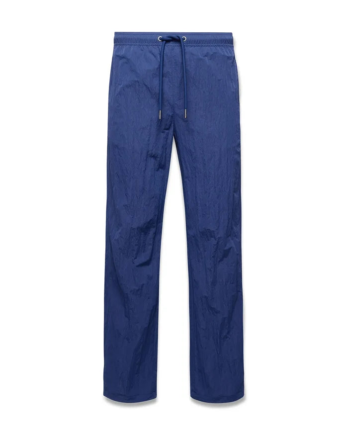 Mens Alder Nylon Pant in deep blue, featuring a relaxed straight leg fit, crinkled nylon fabric, and an elasticated drawstring waist with metallic tips.