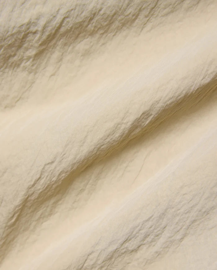 Mens Alder Nylon Pant in a sophisticated light beige hue, showcasing its premium, subtly textured and crinkled nylon fabric with a refined, fine weave, ideal for refined streetwear.