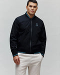 Black Mens Aldrin Bomber jacket, classic fit, featuring a full zip, teal and white striped ribbed collar and cuffs, and an embroidered light blue Psycho Bunny skull logo on the left chest.