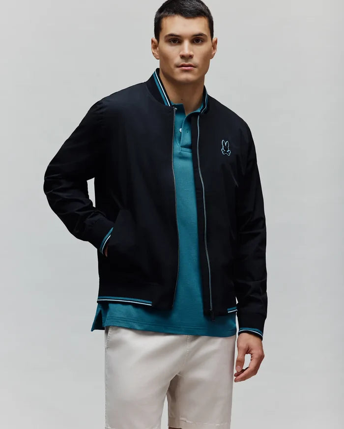 Black Mens Aldrin Bomber jacket with teal and white striped ribbed collar, cuffs, and hem, featuring a full zip with teal trim and a small embroidered teal Psycho Bunny skull logo on the left chest.