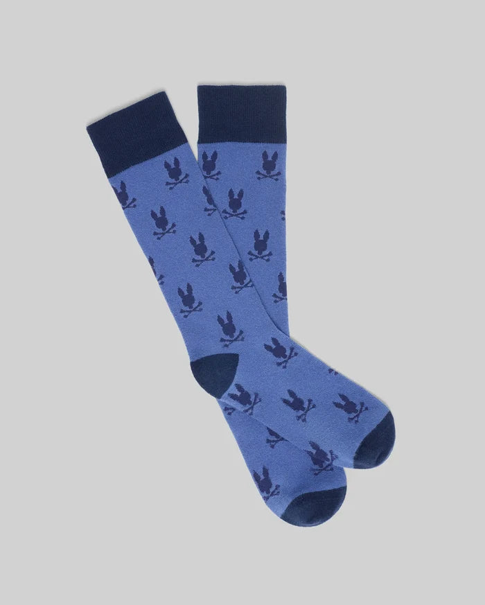 Mens All Over Bunny Dress Sock in medium blue, featuring a seamless all-over dark navy Psycho Bunny skull logo pattern and solid navy cuffs, heels, and toes.