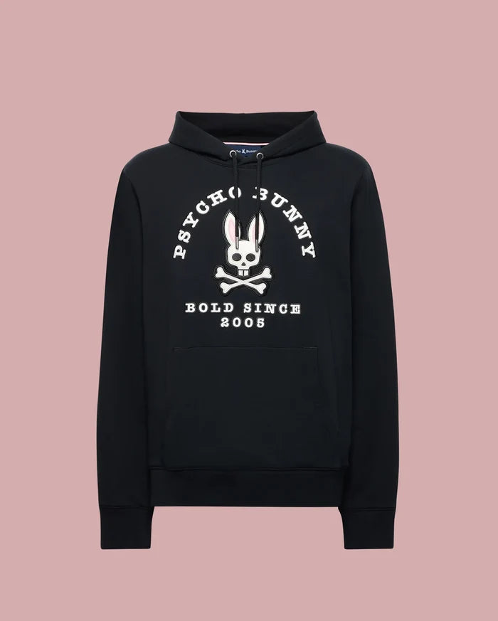 The Psycho Bunny MENS ARCHIVE HOODIE (MT0500009) is a black cotton knit pullover with a front pocket, showcasing an archive-inspired white Bunny skull and crossbones and "PSYCHO BUNNY BOLD SINCE 2005" over a light pink backdrop.