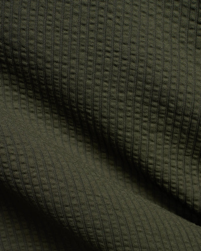 Mens Arlen Relaxed Seersucker Tee in deep olive green, showcasing its distinctive vertical puckered seersucker knit texture with subtle shadows.