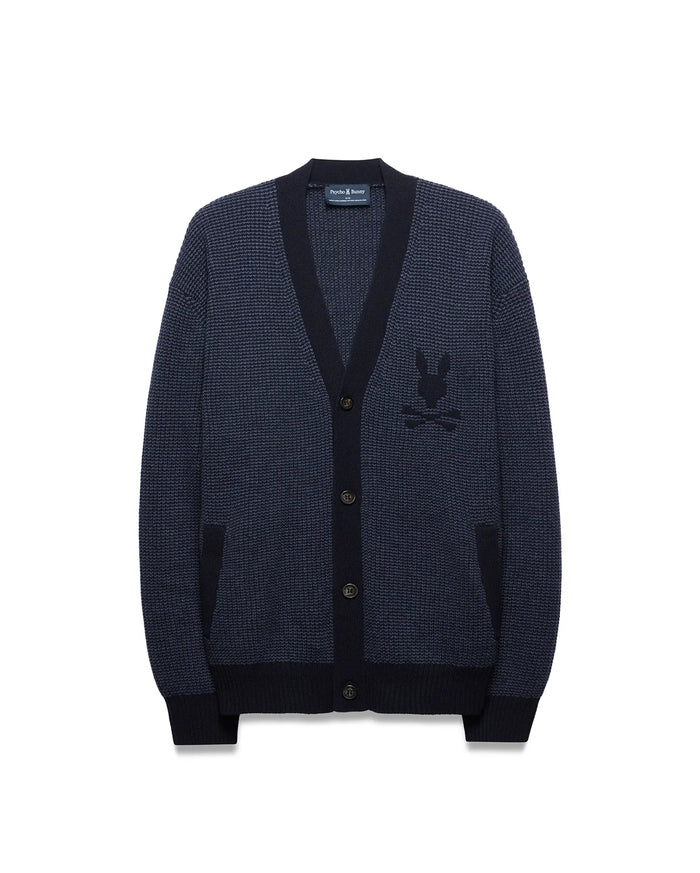 Mens Atkinson Cardigan, a navy blue waffle knit with dark navy ribbed V-neck, cuffs, and hem. Features a button-front, two patch pockets, and a prominent embroidered Psycho Bunny skull logo on the left chest.