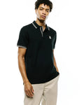 Mens Atley Pique Polo, a classic fit black pique knit polo with white double-stripe tipping on the collar and cuffs, featuring a small white embroidered Psycho Bunny skull logo on the left chest.