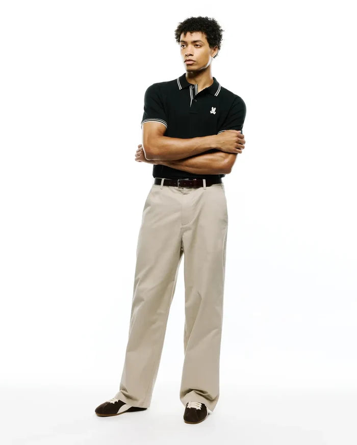 Black Mens Atley Pique Polo with a classic fit, featuring a pique texture, white double-stripe collar and cuffs, and a small embroidered white Psycho Bunny skull logo on the left chest.