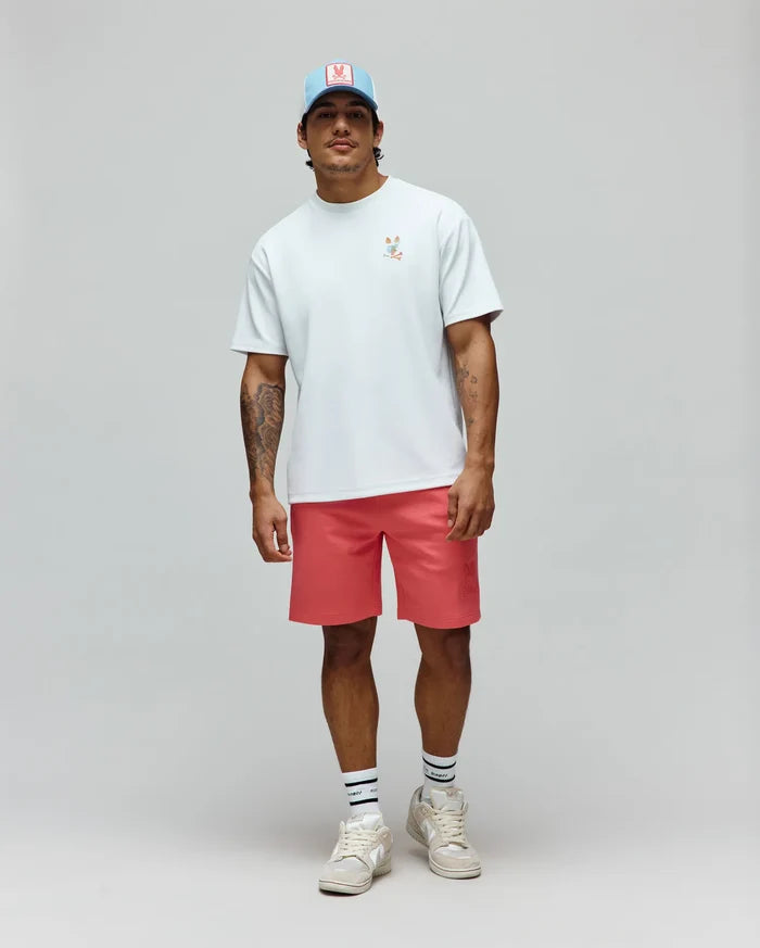 Pale blue jersey t-shirt with a small colorful embroidered Psycho Bunny logo, coral Mens Barry Short with a large tonal embossed bunny skull, and a light blue trucker hat with a pink logo patch.