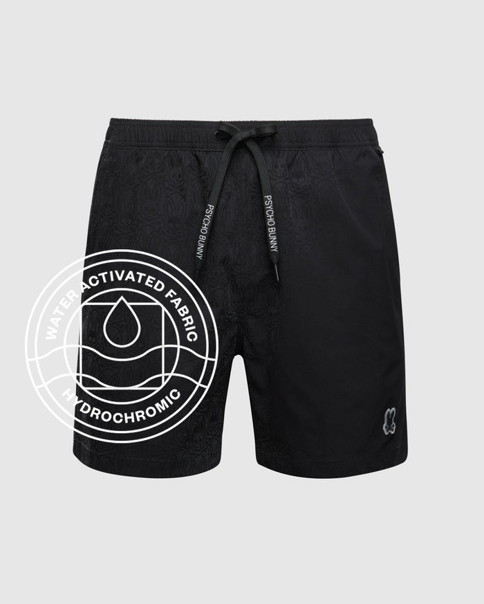 The Psycho Bunny MENS BIG AND TALL SAMOS HYDROCHROMIC SWIM TRUNK (B9W453F200) features black quick-dry fabric, a drawstring waistband, subtle pattern, small leg logo, and "Water Activated Fabric Hydrochromic" circular graphic. Shown on grey background.