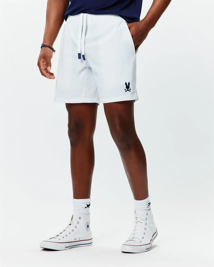 Mens Blaze Sport Short, white, relaxed fit, smooth performance fabric, featuring navy drawstring tips and a small embroidered navy Psycho Bunny skull logo on the lower left leg.