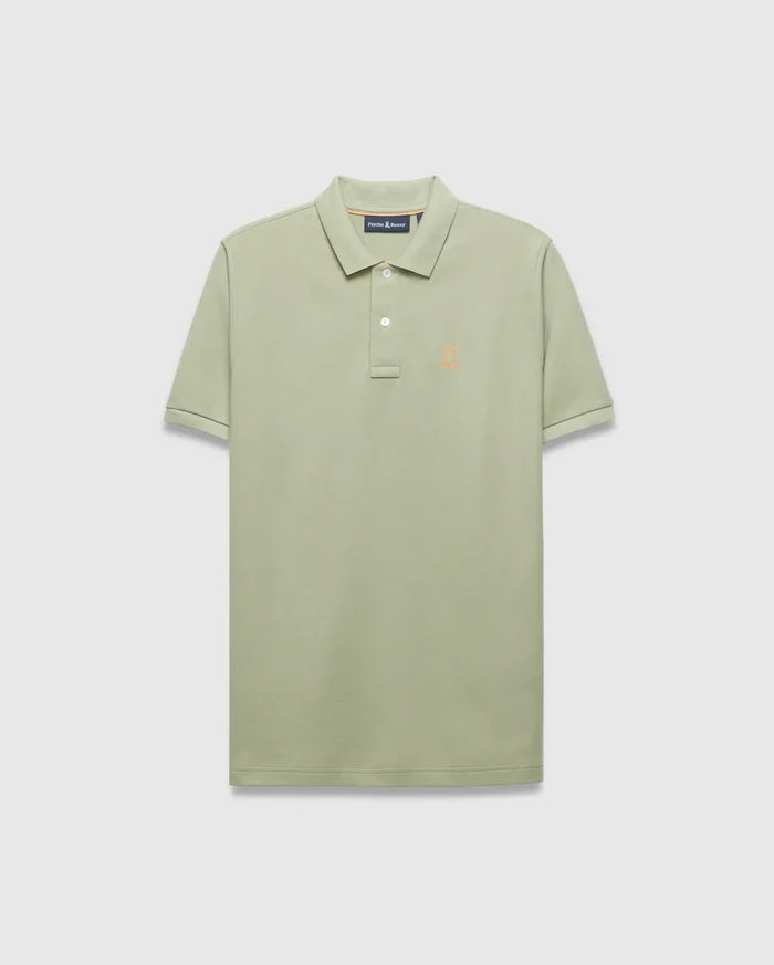 Mens Blythe Pique Polo in sage green, a classic fit polo with textured pique fabric, two-button placket, and a small embroidered orange Psycho Bunny skull logo on the left chest.