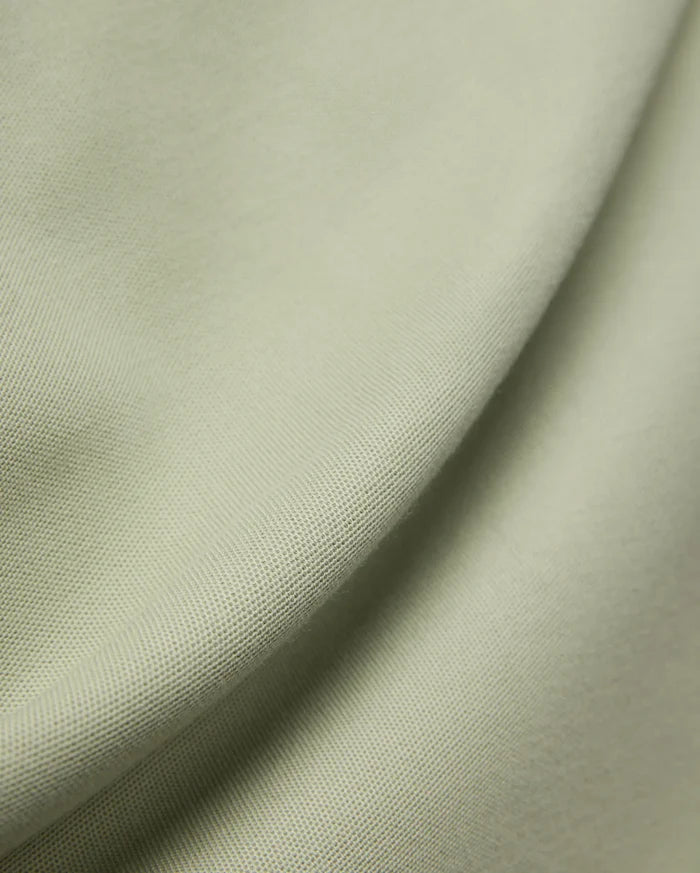 MENS BLYTHE PIQUE POLO, featuring a luxurious, breathable light sage green pique fabric with a distinctive textured weave, reflecting Psycho Bunny's premium menswear quality.