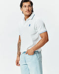 Mens Brad Pique Polo: White classic fit pique polo with blue tipped collar and cuffs, featuring a small embroidered blue Psycho Bunny skull logo on the left chest.