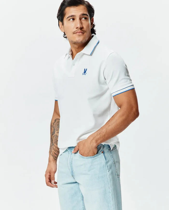 Mens Brad Pique Polo: White classic fit pique polo with blue tipped collar and cuffs, featuring a small embroidered blue Psycho Bunny skull logo on the left chest.