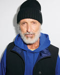 Black ribbed knit MENS BROGAN BEANIE with a subtle bunny skull logo patch, layered over a royal blue relaxed fit french terry hoodie and a black full-zip vest with a dark blue collar and branded snap button.