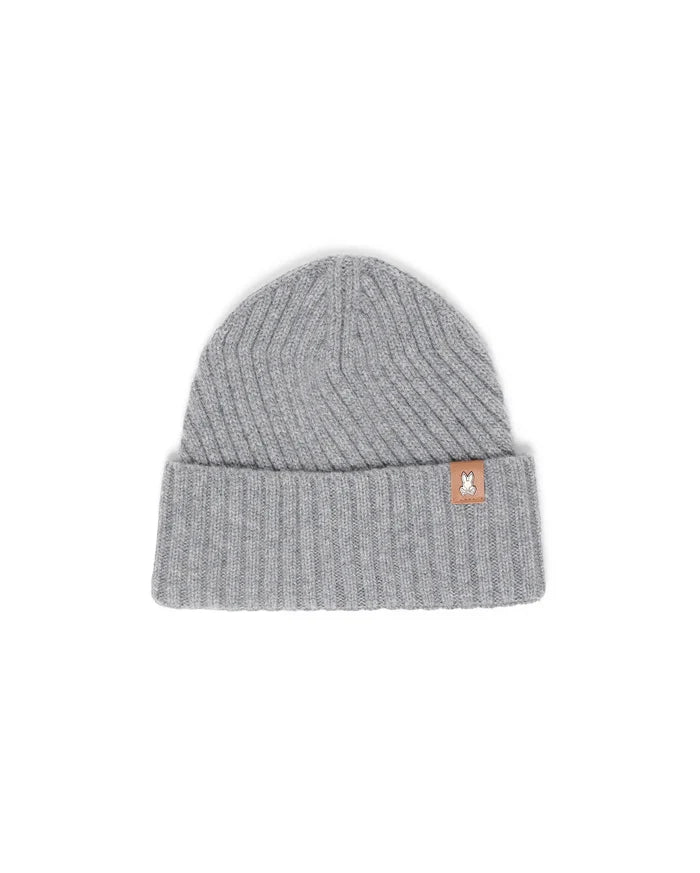 Mens Brogan Beanie, a grey ribbed knit beanie with a classic fit and a folded cuff, featuring a small brown leather-like patch on the front cuff with the iconic white Psycho Bunny skull logo.