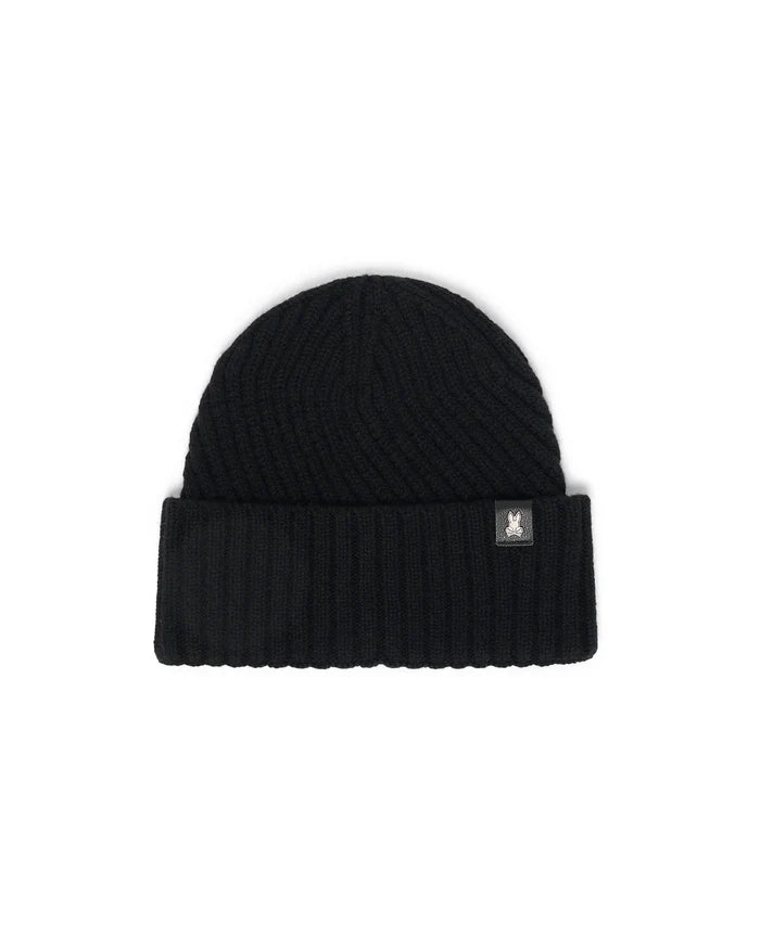 Black Mens Brogan Beanie, a premium ribbed knit beanie featuring a classic folded cuff and a distinctive small white Psycho Bunny skull logo patch on the front.