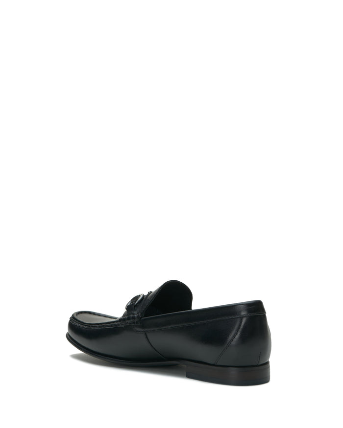 The Vince Camuto Men’s Caelan Loafer is displayed at an angle on a white background, showcasing its black leather construction, detailed stitching, and sleek heel—making it an ideal office shoe.