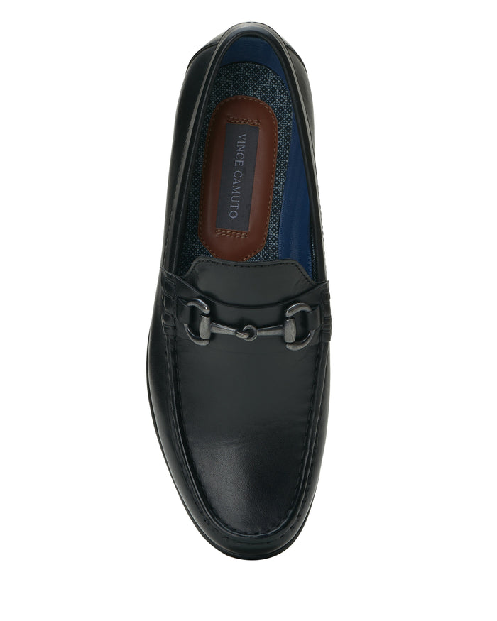 A top-view image of the Vince Camuto Men’s Caelan Loafer, featuring black leather, a moccasin toe, silver horse-bit hardware detail, visible stitching, and a brown insole branded with Vince Camuto, set against a white background.