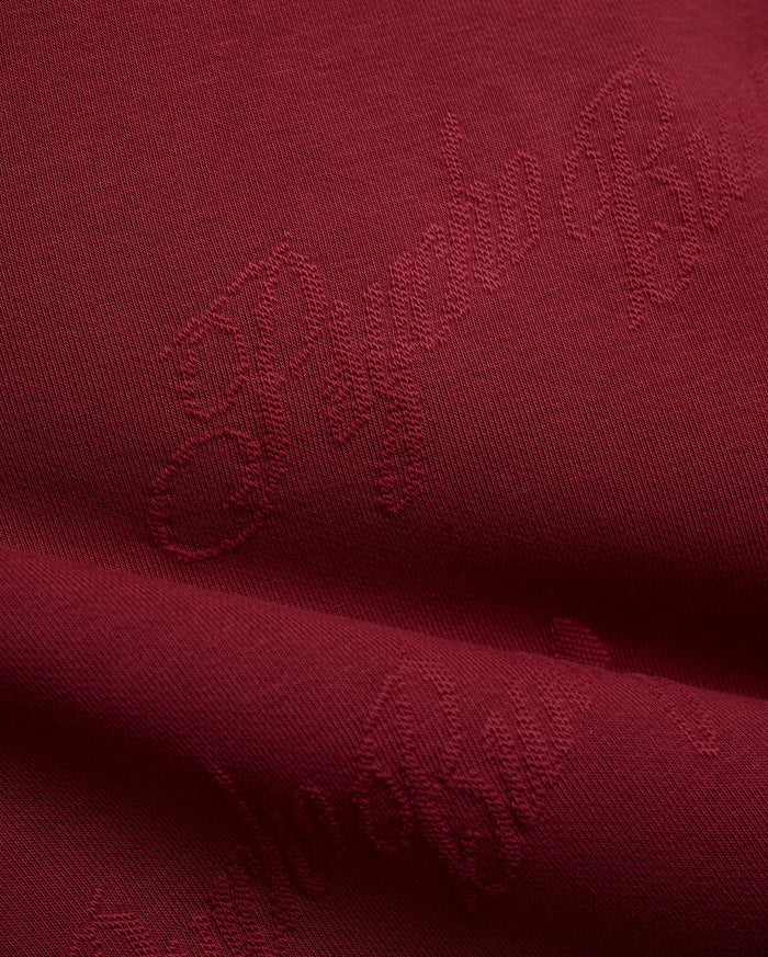 Mens Cedrick All Over Jacquard Crew in deep burgundy, featuring a subtle tone-on-tone jacquard knit pattern of the Psycho Bunny logo and brand name.