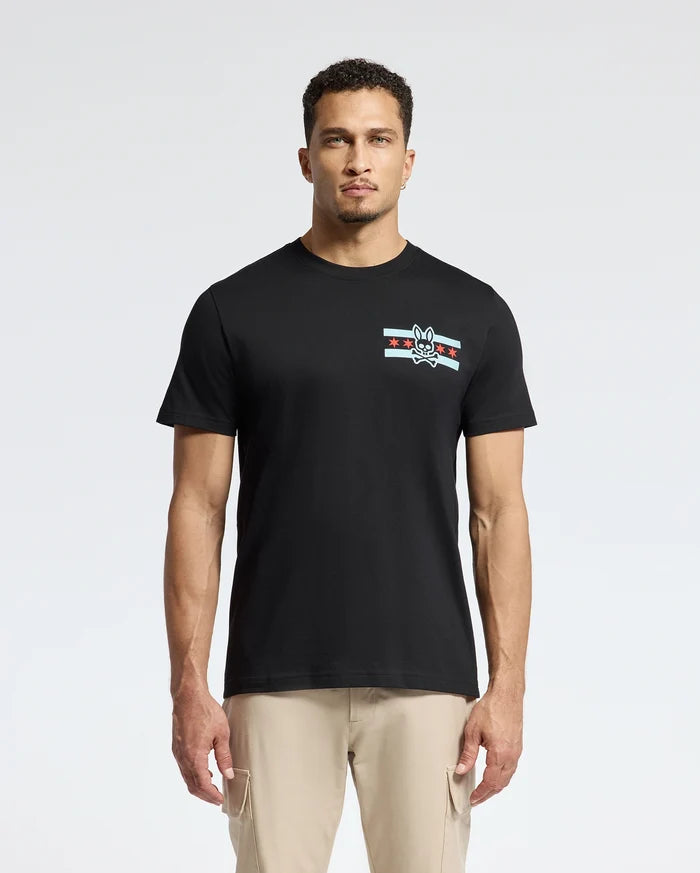 A man wearing the Psycho Bunny MENS CHICAGO TEE - B6U551W1PC, crafted from soft Pima cotton and featuring a small graphic design with stripes and a rabbit emblem on the left chest, is complemented by light beige pants as he stands confidently against a plain white background.