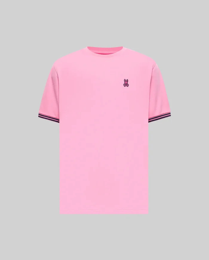Mens Clark Performance Tee in bright pink jersey knit, featuring a classic fit, small embroidered purple Psycho Bunny skull logo on the left chest, and ribbed sleeve cuffs with dark blue stripes.