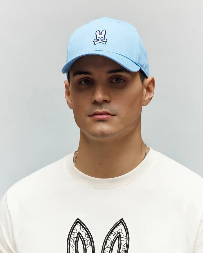 Mens Classic Baseball Cap in a vibrant light blue, crafted from smooth cotton twill, featuring a detailed embroidered white and navy Psycho Bunny skull logo prominently centered on the front panel.