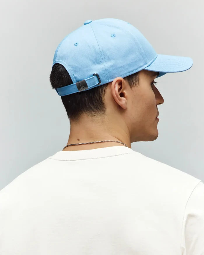 Mens Classic Baseball Cap in light blue smooth cotton twill, featuring an adjustable strap with a gunmetal buckle embossed with the small Psycho Bunny skull logo at the back.