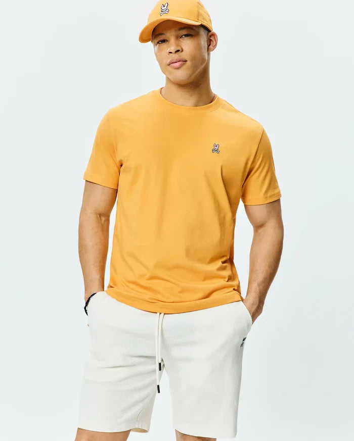 Mens Classic Crew Neck Tee in bold golden yellow, crafted from soft jersey knit with a classic fit, featuring a small, signature embroidered Psycho Bunny skull logo on the left chest.