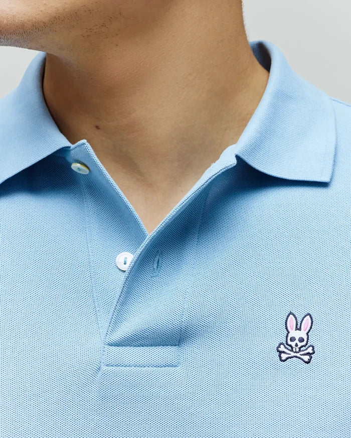 Light blue Mens Classic Pique Polo with a classic fit, pique knit texture, two-button placket, and a small embroidered white, pink, and black Psycho Bunny skull logo on the left chest.