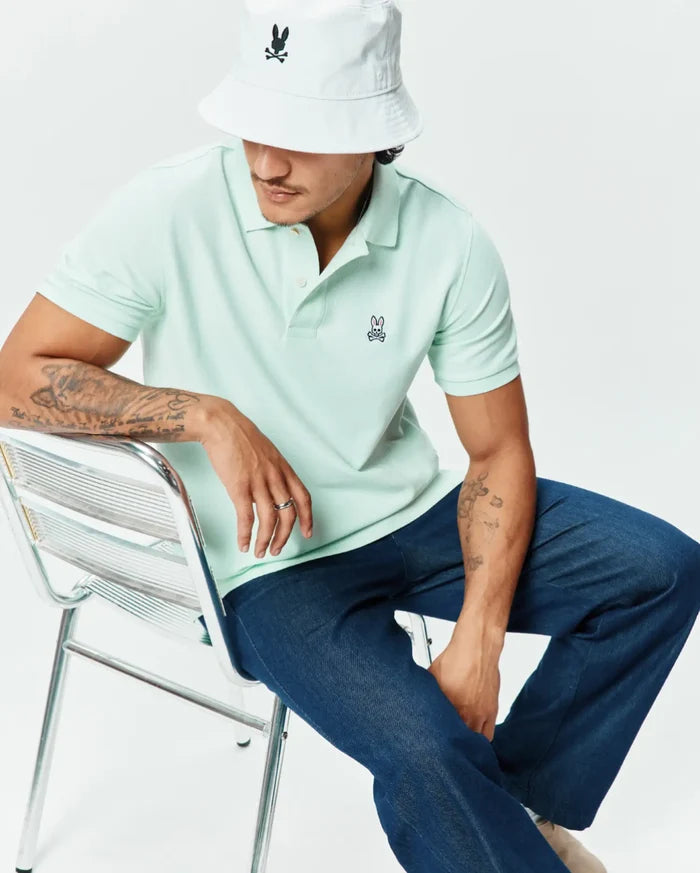 Pale mint green Mens Classic Pique Polo, classic fit, with a two-button placket and small embroidered dark blue and pink Psycho Bunny skull logo on the left chest.