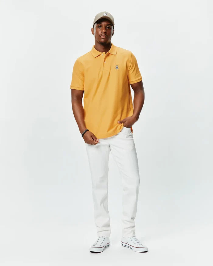 Mens Classic Pique Polo in golden orange, featuring a classic fit, textured pique fabric, and a small, embroidered multi-color Psycho Bunny skull logo on the left chest.