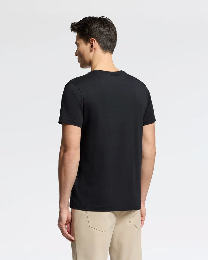 A person with short dark hair, standing sideways against a light gray background, wears a black MENS CLASSIC V NECK TEE - B6U100ARPC by Psycho Bunny and beige pants.