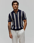Mens Cliff Knit Zip Polo in navy and cream vertical stripes, featuring a quarter-zip placket, ribbed knit texture, classic fit, and a small embroidered Psycho Bunny skull logo on the left chest.