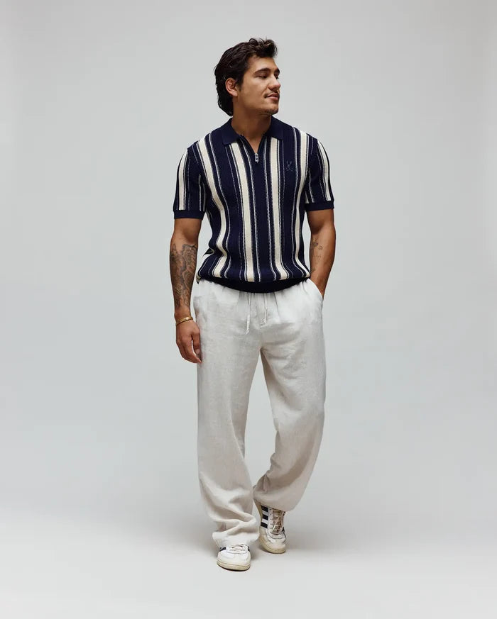 Mens Cliff Knit Zip Polo, a classic fit navy and cream vertical striped textured knit polo with a half-zip and embroidered Psycho Bunny skull logo on the left chest.