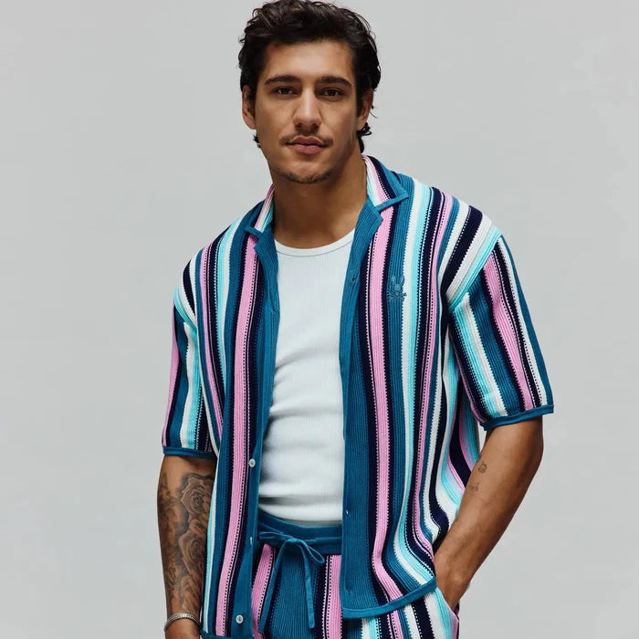 Mens Cliff Shirt, a vibrant knit short-sleeve shirt with teal, pink, light blue, white, and navy vertical stripes, featuring a small embroidered Psycho Bunny skull logo on the left chest.