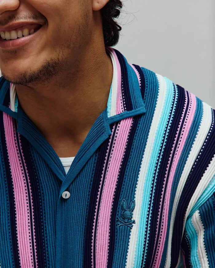 Mens Cliff Shirt, a vibrant ribbed knit polo with vertical stripes in navy, teal, light blue, pink, and white, featuring a small embroidered Psycho Bunny skull logo on the left chest.