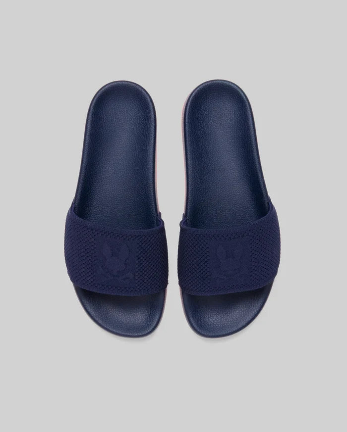 Mens Contrast Sole Knit Slides in navy with a textured knit strap featuring a woven Psycho Bunny skull logo and a subtle pink contrast sole.