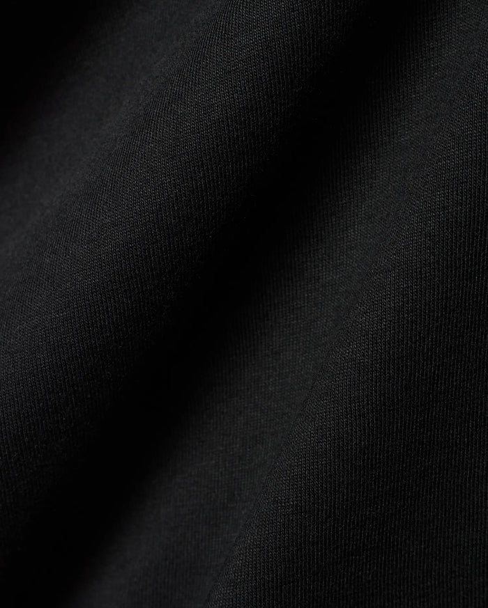Black Mens Dariel Long Sleeve Back Graphic Tee, crafted from premium, soft jersey knit fabric with subtle vertical texture and elegant folds, reflecting refined streetwear quality.