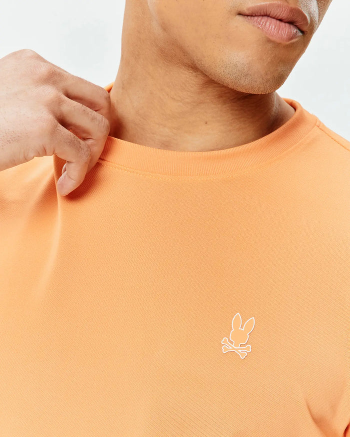 Mens Dash Bunny Sport Tee in peach pique knit, featuring a small white embroidered Psycho Bunny skull logo on the left chest, offering a classic fit.