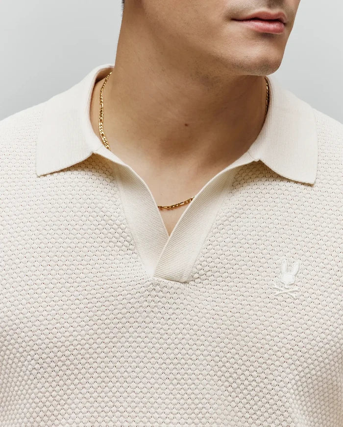 Mens Devon Knit Polo in cream, featuring a textured knit fabric, classic collar, V-neck placket, and a small embroidered cream Psycho Bunny skull logo on the left chest.