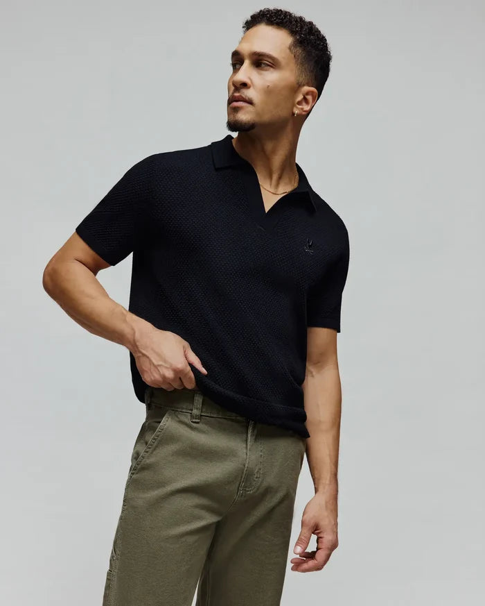 Black Mens Devon Knit Polo, a classic fit short-sleeve textured knit polo featuring a small, tonal embroidered Psycho Bunny skull logo on the left chest.