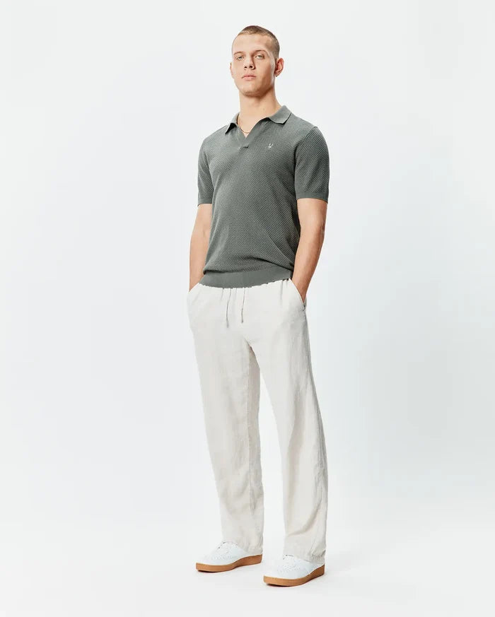 Mens Devon Knit Polo, a classic fit charcoal textured knit polo shirt featuring a subtle geometric pattern and a small embroidered Psycho Bunny skull logo on the left chest.