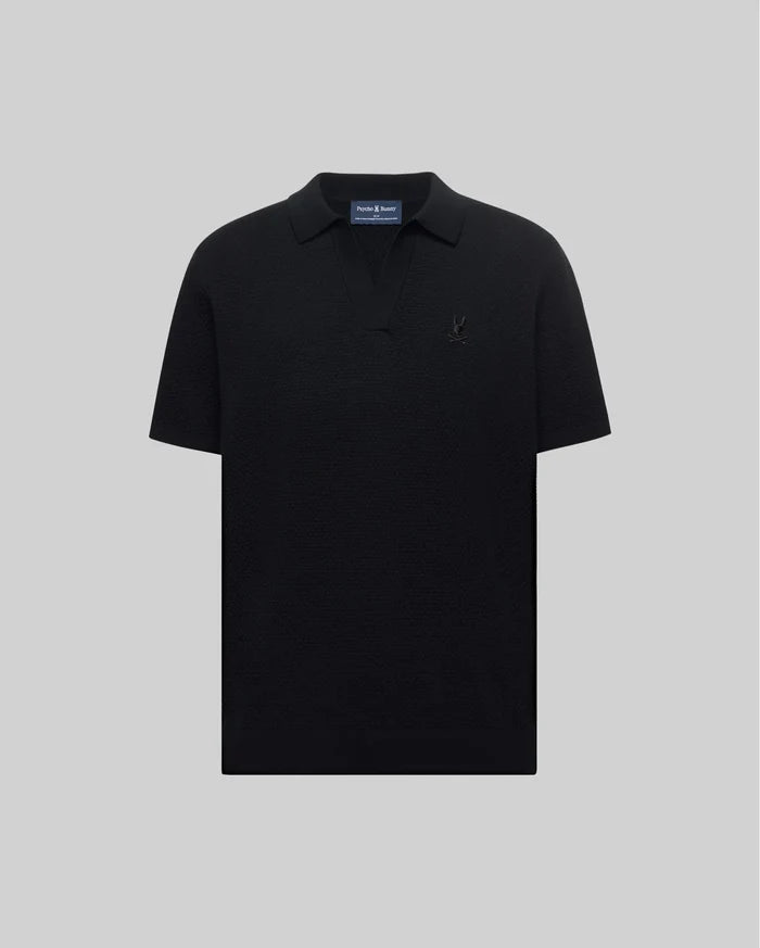Mens Devon Knit Polo in black, featuring a subtle textured knit, classic fit, V-neck placket, and a tonal embroidered Psycho Bunny skull logo on the left chest.