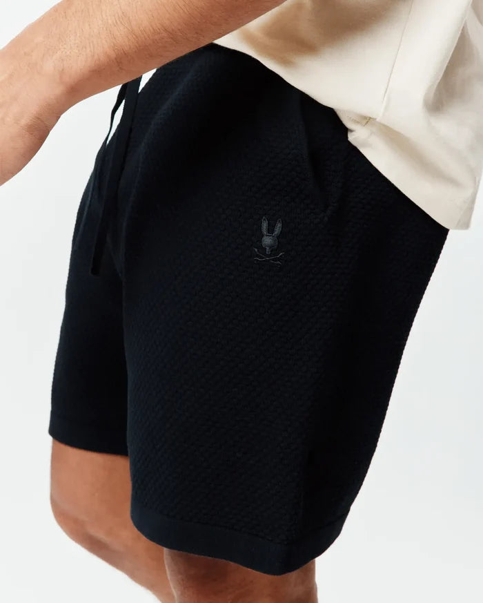 Psycho Bunny Black Mens Devon Knit Short, a relaxed fit with textured knit fabric, drawstring waist, and small tonal embroidered bunny skull logo on the left thigh.
