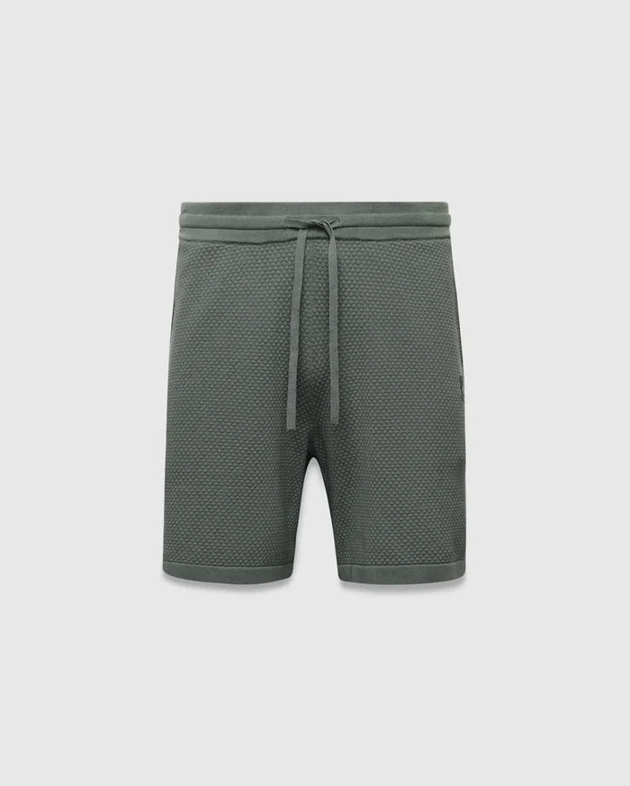 Mens Devon Knit Short 7, a sage green relaxed fit pique knit short with a drawstring waist, ribbed waistband, and a small embroidered Psycho Bunny skull logo on the right thigh.