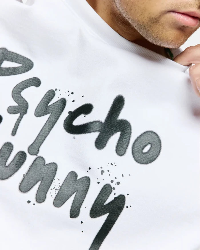 White Mens Duncan Wordmark Relaxed Fit Tee in soft jersey, featuring a large dark grey graffiti-style Psycho Bunny wordmark print with paint splatters on the chest.