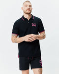 Mens Duncan Pique Polo, black with pink collar and cuff tipping. Features an embroidered pink Psycho Bunny chest logo, small sleeve bunny skull, and pink side vents. Classic fit.