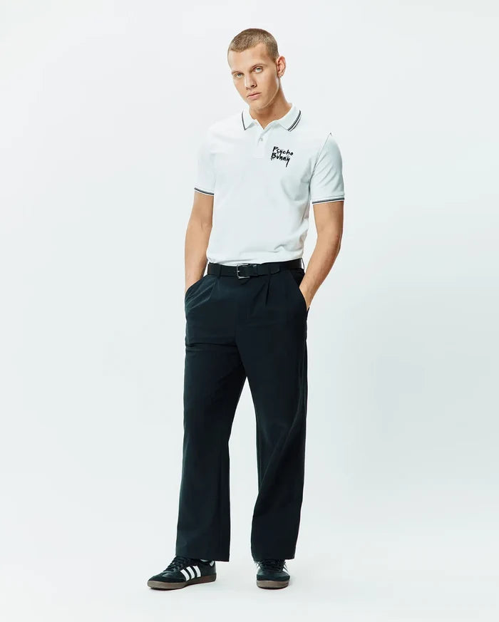 Mens Duncan Pique Polo, white pique, classic fit, with black striped collar and cuffs, featuring an embroidered black Psycho Bunny script logo on the left chest.