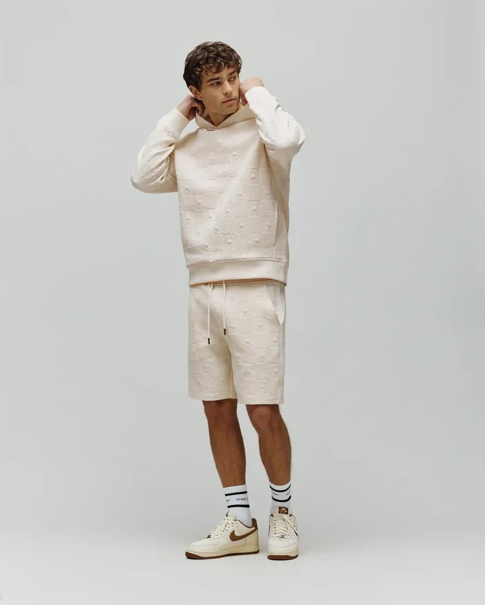 Mens Dustin Sweatshort and matching relaxed fit cream hoodie, both with an allover embossed Psycho Bunny skull logo pattern. Small embroidered bunny logo on hoodie chest, black drawstring tips.